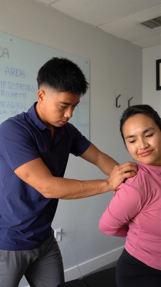 Dr. Jaron Hua treating a patient's shoulder by hand at G3 Chiro in Newport Beach